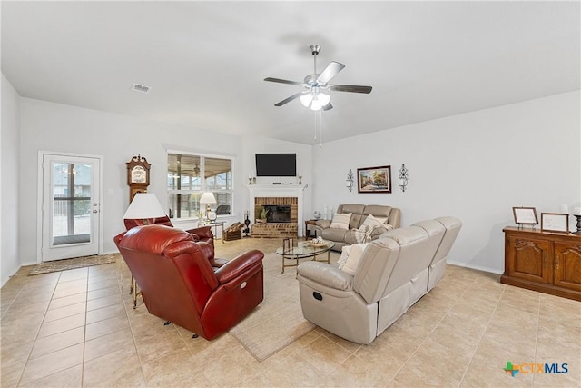 tiled living room featuring ceiling fan and a brick fireplace