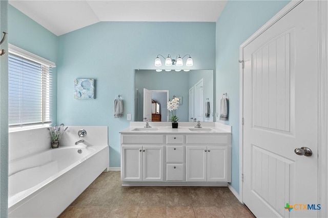 bathroom with lofted ceiling, vanity, tile patterned floors, and a tub to relax in