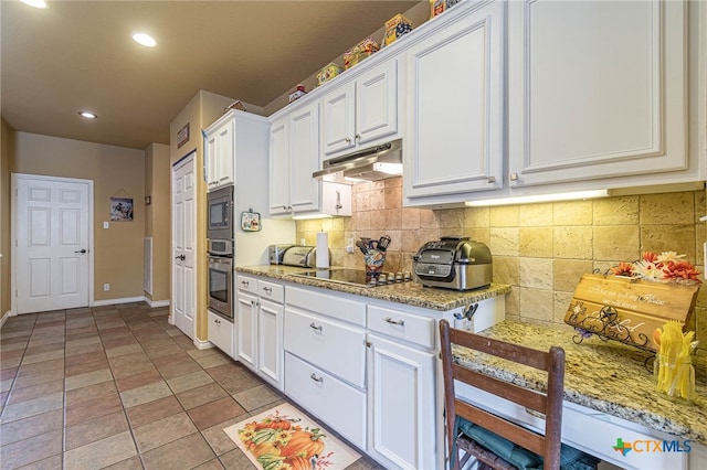 kitchen with decorative backsplash, light stone countertops, black appliances, white cabinets, and light tile patterned flooring