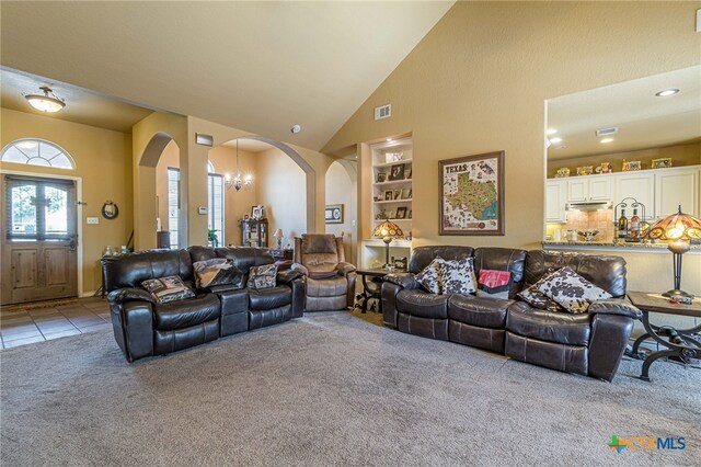 living room featuring a chandelier, built in shelves, light colored carpet, and high vaulted ceiling