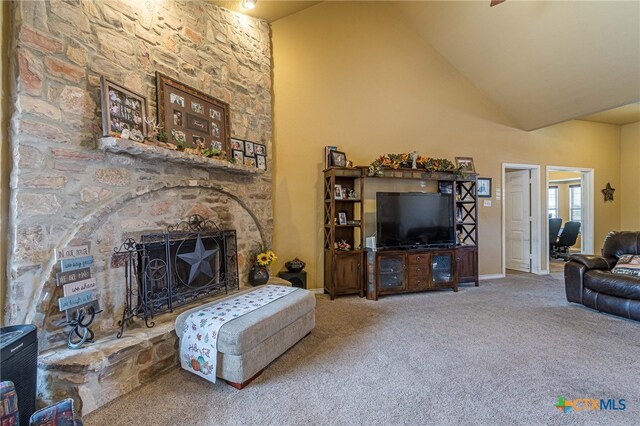 carpeted living room with a fireplace and high vaulted ceiling