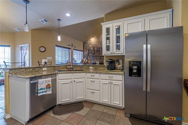 kitchen featuring a healthy amount of sunlight, white cabinetry, stainless steel appliances, and vaulted ceiling