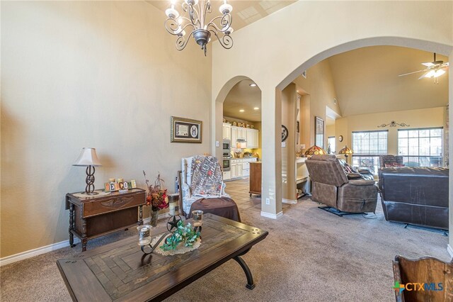 living room with light carpet, ceiling fan with notable chandelier, and high vaulted ceiling