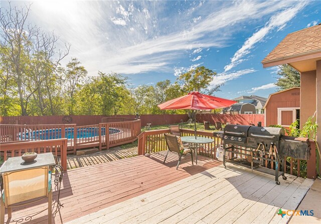 wooden deck with a pool and a storage shed