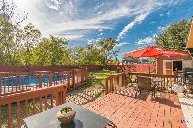 wooden terrace featuring a fenced in pool and a storage shed