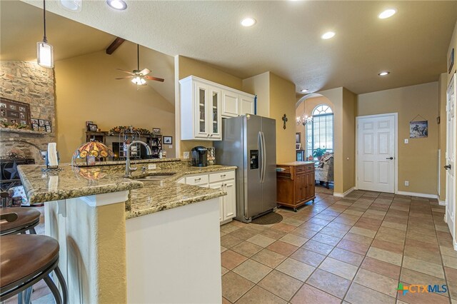 kitchen featuring white cabinets, kitchen peninsula, stainless steel refrigerator with ice dispenser, and a breakfast bar area