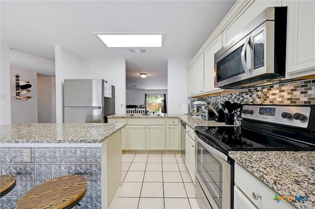 7410 Tom Watson Ct, San Antonio, TX 78244 - kitchen featuring stainless steel appliances, light tile patterned floors, tasteful backsplash, a peninsula, and light stone counters