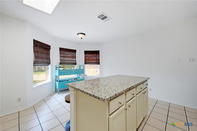 7410 Tom Watson Ct, San Antonio, TX 78244 - kitchen featuring light tile patterned floors, baseboards, a center island, and light stone countertops