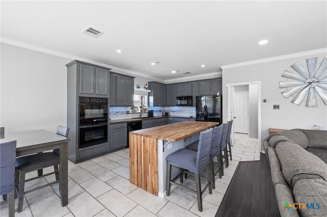 4904 Sodalite Ct, Killeen, TX 76542 - kitchen with black appliances, wooden counters, a kitchen bar, ornamental molding, and open floor plan