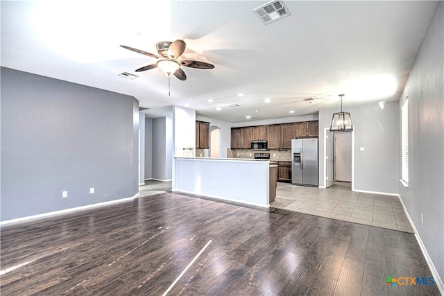 kitchen featuring pendant lighting, ceiling fan, stainless steel appliances, decorative backsplash, and light wood-type flooring