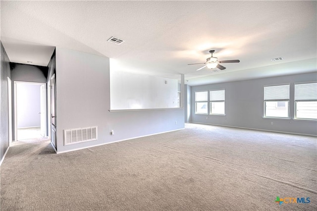 empty room featuring a textured ceiling, light colored carpet, and ceiling fan