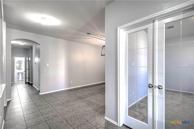 corridor featuring french doors and a textured ceiling