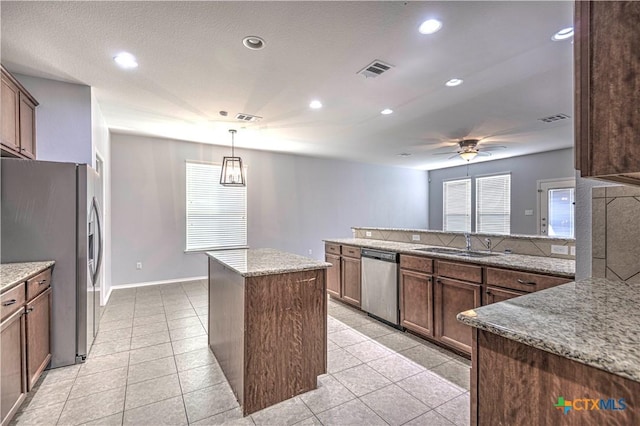 kitchen with sink, a center island, pendant lighting, ceiling fan, and stainless steel appliances