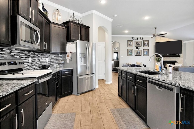 kitchen with sink, stainless steel appliances, ornamental molding, light hardwood / wood-style floors, and decorative backsplash