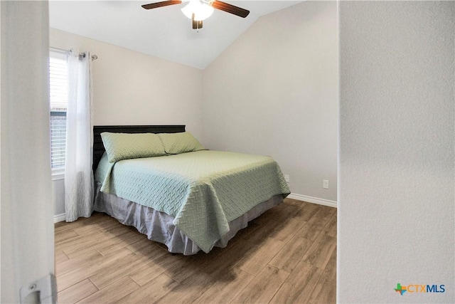 bedroom with light hardwood / wood-style flooring, vaulted ceiling, and ceiling fan