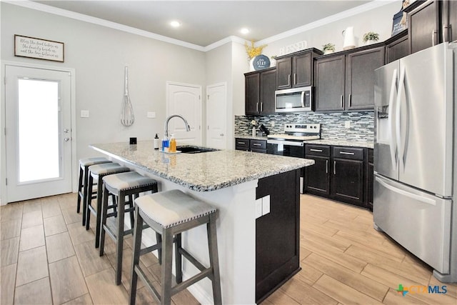 kitchen with stainless steel appliances, sink, an island with sink, and a breakfast bar area