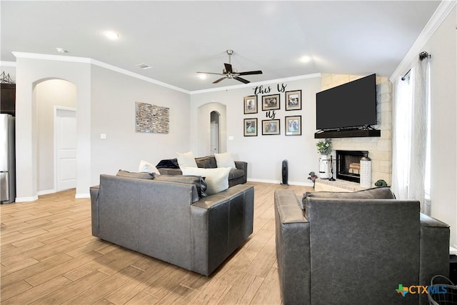 living room featuring crown molding, a large fireplace, and light wood-type flooring