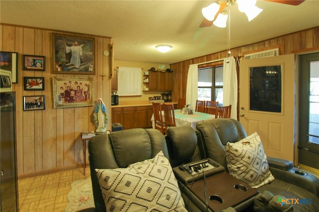 living room with ceiling fan and wood walls