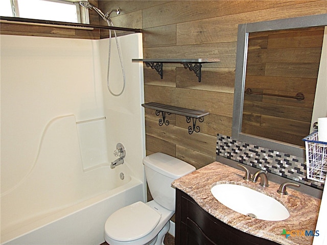 full bathroom featuring vanity, wood walls, toilet, and shower / washtub combination