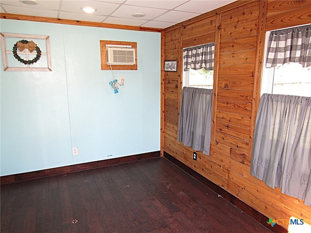 spare room with an AC wall unit, wood walls, dark hardwood / wood-style flooring, and a drop ceiling