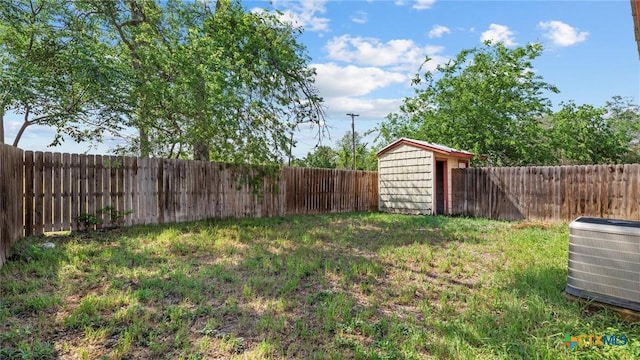 view of yard with an outbuilding, a storage shed, central air condition unit, and a fenced backyard