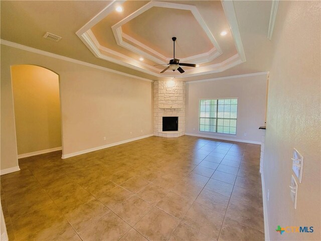 6409 Jovana Dr, Killeen, TX 76542 - unfurnished living room with a ceiling fan, a tray ceiling, a fireplace, light tile patterned floors, and arched walkways