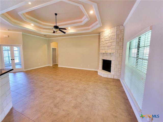 6409 Jovana Dr, Killeen, TX 76542 - unfurnished living room featuring ceiling fan, crown molding, a stone fireplace, a tray ceiling, and arched walkways