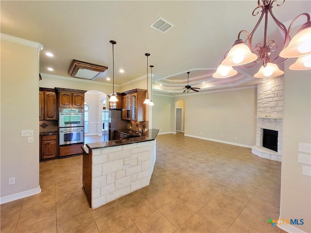 6409 Jovana Dr, Killeen, TX 76542 - kitchen featuring arched walkways, stainless steel appliances, dark countertops, ornamental molding, and a fireplace