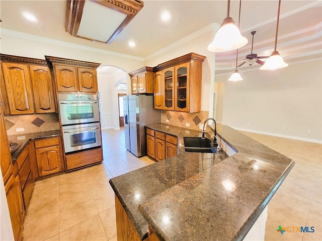 6409 Jovana Dr, Killeen, TX 76542 - kitchen featuring appliances with stainless steel finishes, arched walkways, brown cabinetry, ceiling fan, and crown molding