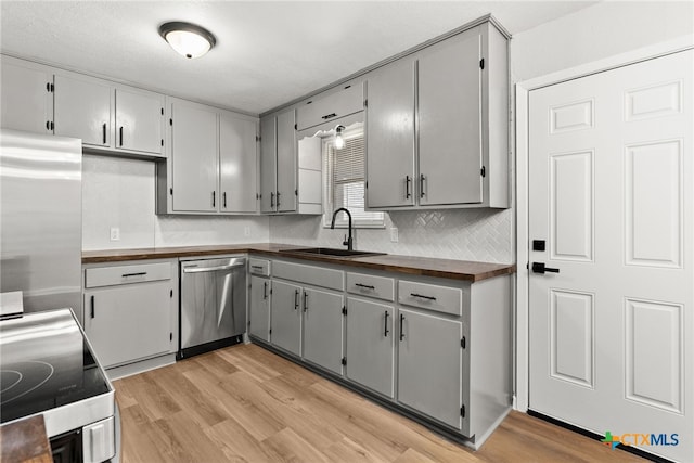 kitchen with light hardwood / wood-style floors, stainless steel appliances, sink, and gray cabinetry