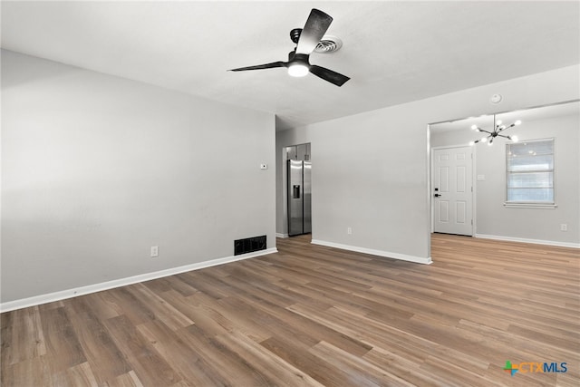 unfurnished living room featuring ceiling fan with notable chandelier and wood-type flooring