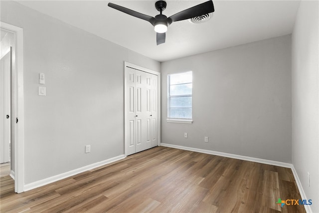 unfurnished bedroom with hardwood / wood-style flooring, ceiling fan, and a closet