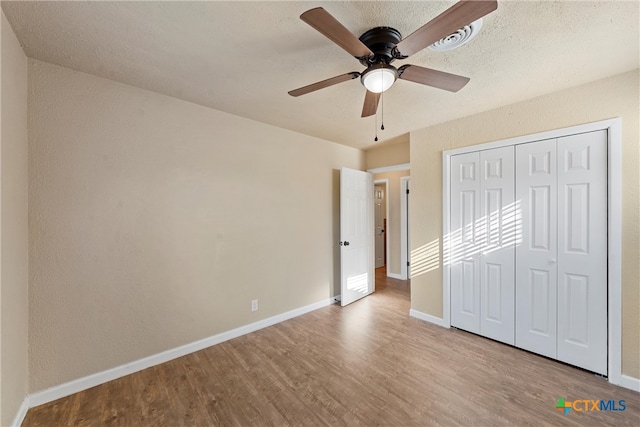 unfurnished bedroom with light hardwood / wood-style floors, ceiling fan, and a closet