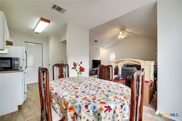 dining area featuring stone finish flooring, visible vents, a ceiling fan, and vaulted ceiling