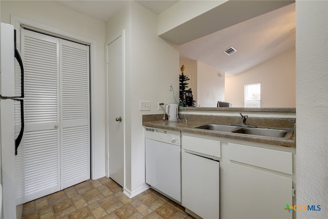 kitchen with white appliances, visible vents, a sink, stone finish floor, and white cabinets