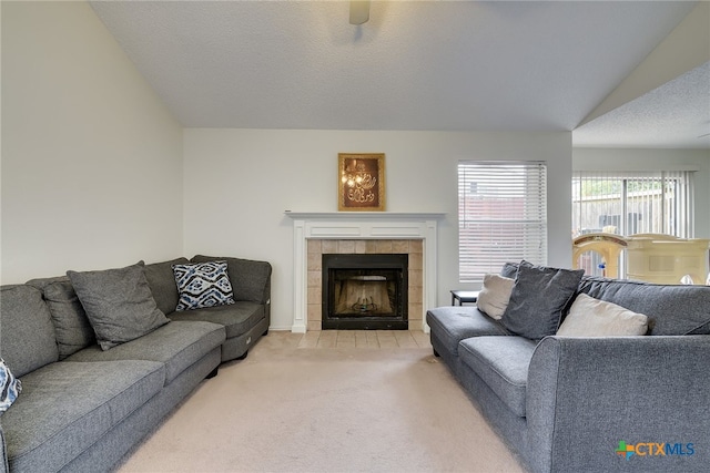 living room featuring a tiled fireplace, light colored carpet, a textured ceiling, and lofted ceiling