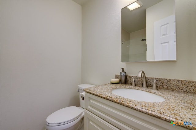 bathroom featuring a shower, toilet, and vanity