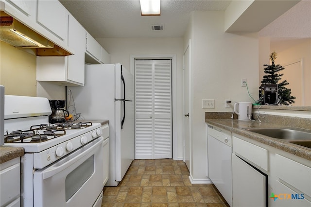 kitchen featuring white appliances, stone finish flooring, under cabinet range hood, a textured ceiling, and white cabinetry