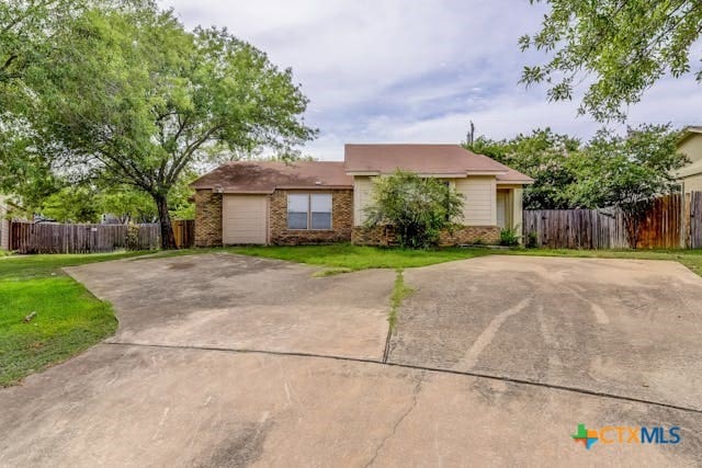 ranch-style home with brick siding, driveway, a front lawn, and fence