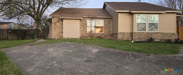 view of front of house with a garage, brick siding, a front yard, and fence