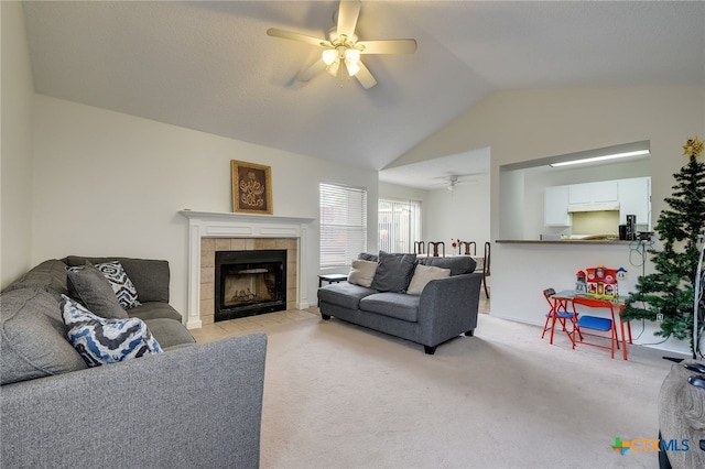 living area with light colored carpet, a fireplace, a ceiling fan, and vaulted ceiling