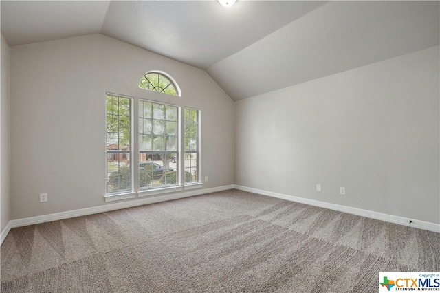 carpeted empty room featuring vaulted ceiling