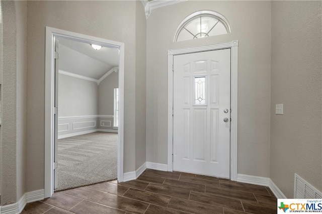 carpeted foyer entrance with lofted ceiling and ornamental molding