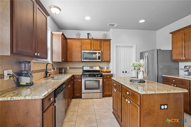 125 Flint Rock Ct, Victoria, TX 77904 - kitchen with appliances with stainless steel finishes, a sink, a center island, light stone countertops, and decorative backsplash