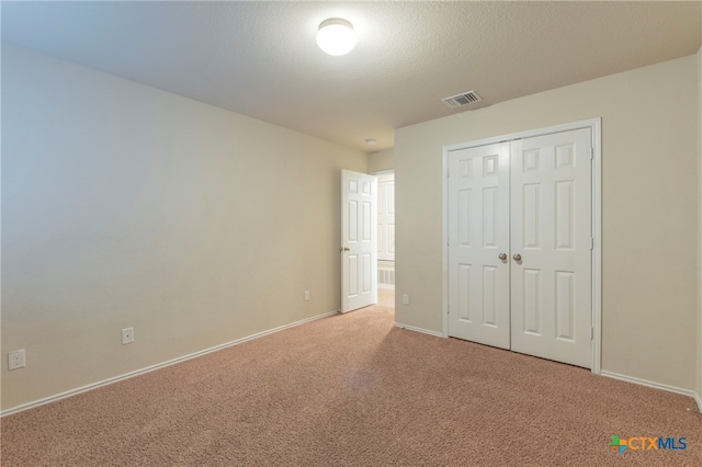 unfurnished bedroom featuring a closet, a textured ceiling, and carpet flooring