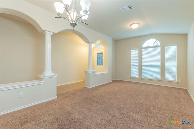 unfurnished living room with ornate columns, light colored carpet, a chandelier, and vaulted ceiling