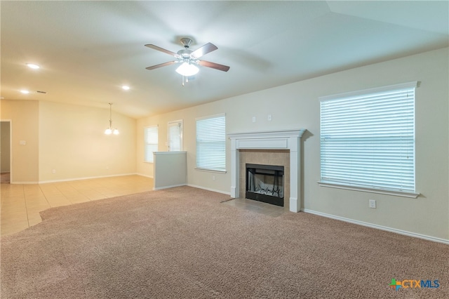 unfurnished living room with vaulted ceiling, light colored carpet, ceiling fan, and a fireplace