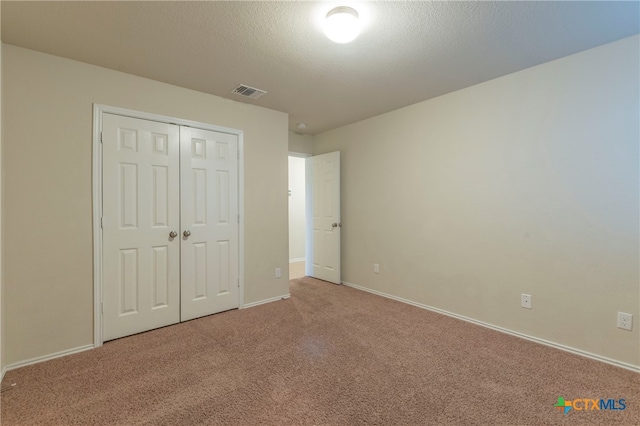 unfurnished bedroom featuring a closet, carpet, and a textured ceiling