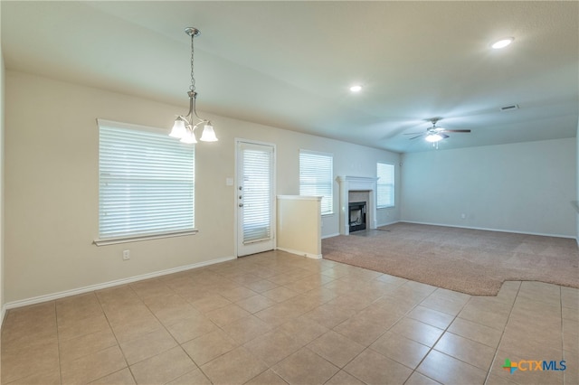 unfurnished living room featuring light carpet and ceiling fan with notable chandelier