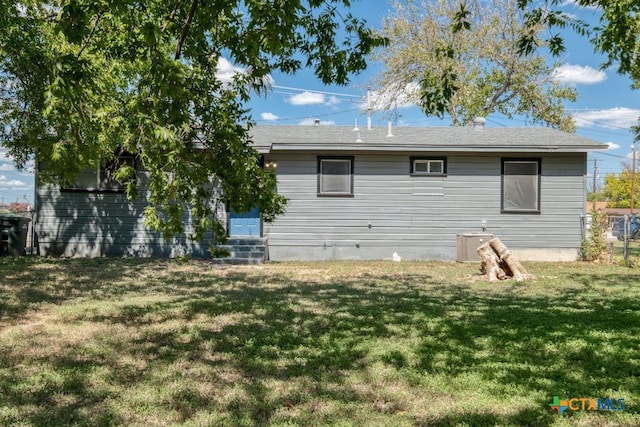 rear view of property featuring a yard and central AC unit